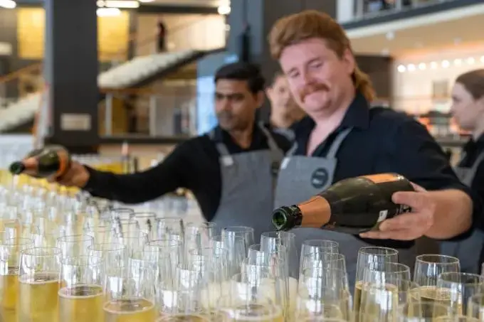 An image of a bartender pouring champagne into glasses